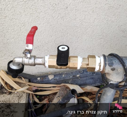 ברז מים עם ידית אדומה וצינור מחובר